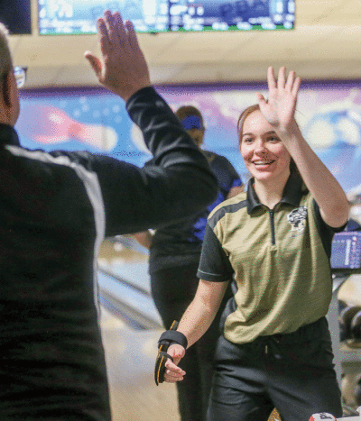  North sophomore Ryann Joslin high-fives coach Darin Driscoll after rolling a strike. 