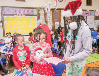  Lauryn Thomas, a Novi Meadows Elementary School student, reads a Christmas card to Academy of the Americas students. 