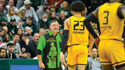  Oakland coach Greg Kampe, sporting festive attire, looks on as Chris Conway (23) and Rocket Watts (3) stand on the court. 