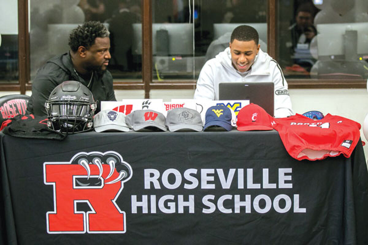  Amare Snowden, right, takes in the moment with his father and Roseville football head coach Vernard Snowden, as Amare Snowden announces his commitment to the University of Wisconsin. 
