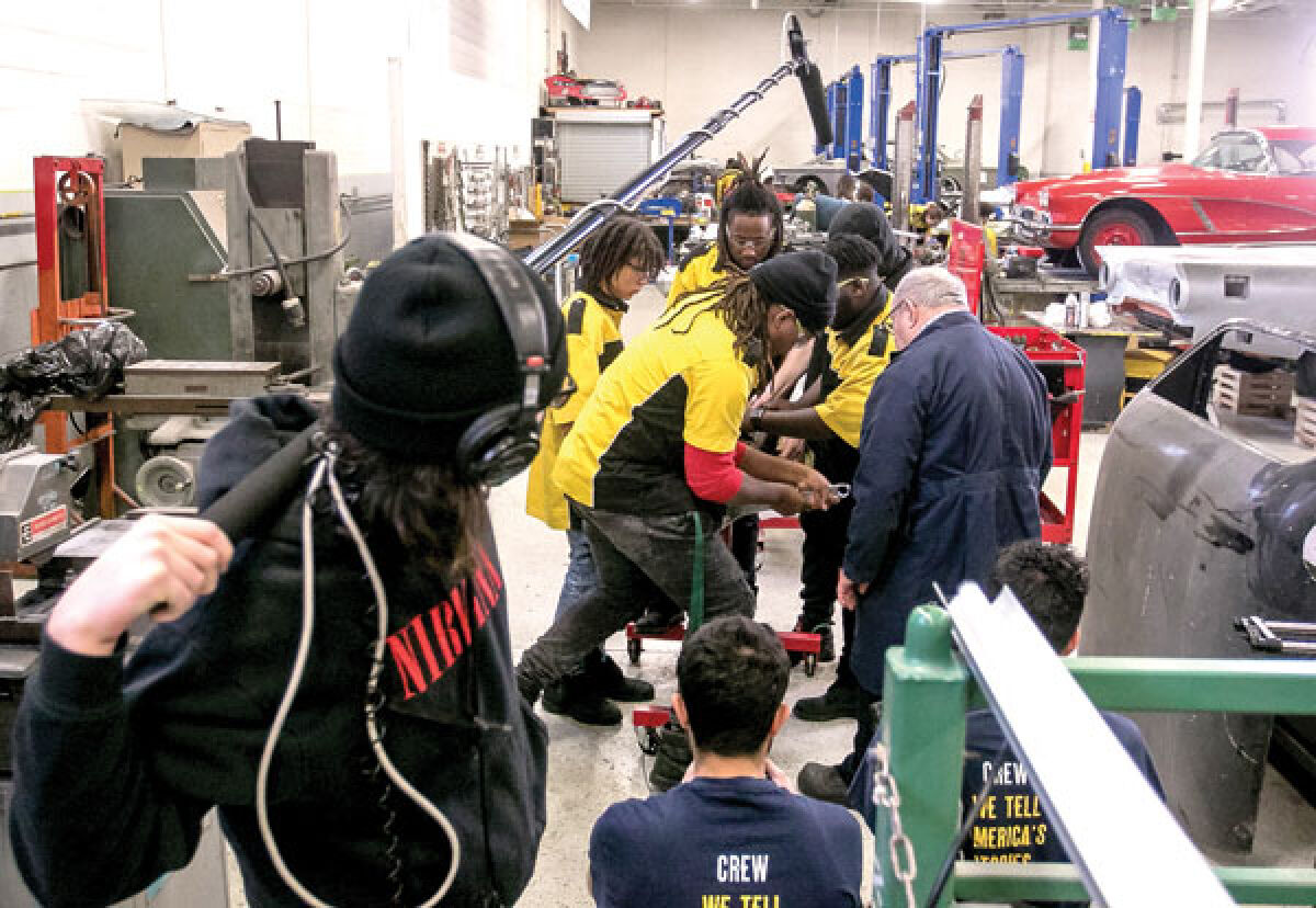  Filming for the Keith Famie documentary “Detroit: The City of Hot Rods & Muscle Cars” takes place at Drive One Detroit on Feb. 2. Here, the camera crew gets a look at South Lake High School students working with Paul Tregembo Sr. on rebuilding an engine. 