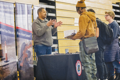  Frank Hines, outreach coordinator for the Michigan Statewide Carpenters and Millwrights, talks with students at the skilled trades fair Feb. 8. 