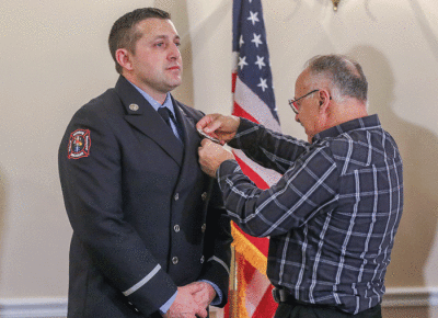   Warren Fire Department Lt. Eric Kamm has his new badge pinned to his uniform by his father, George Kamm. 