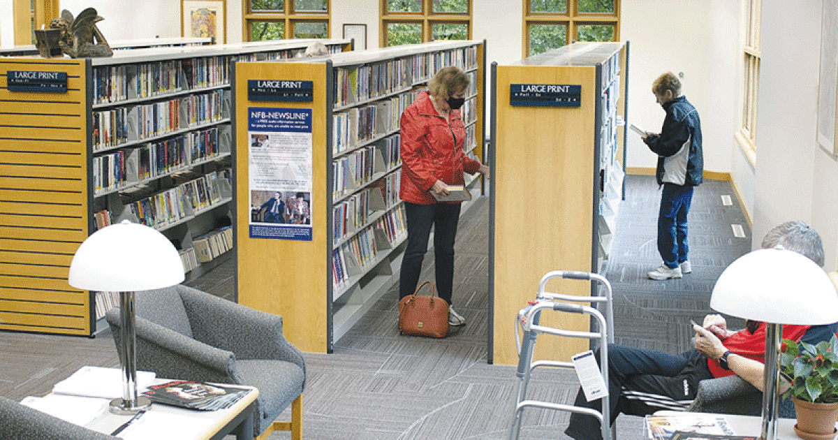 Library patrons search the large print collection in the Outreach and Oakland Talking Book Service Department at the library. 