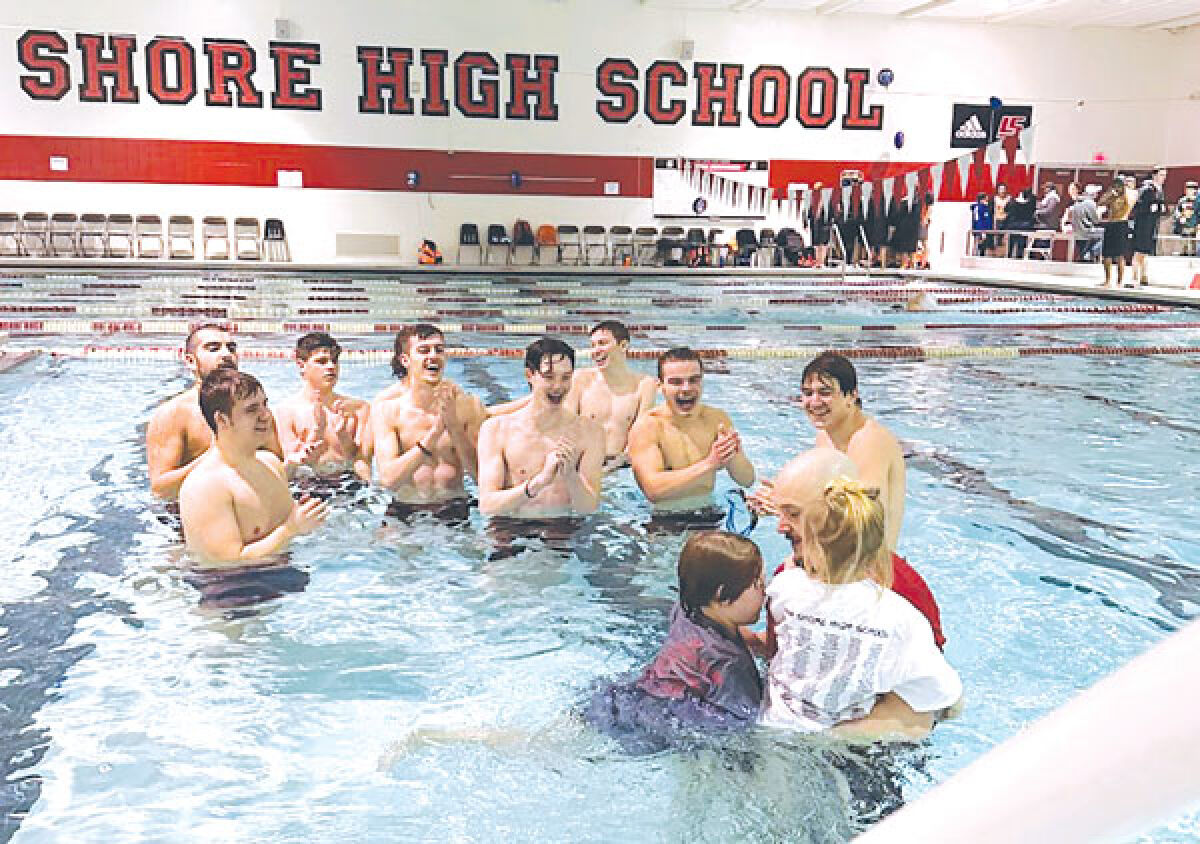  Members of the St. Clair Shores Lake Shore boys swim and dive team celebrate with their coach after a meet. 