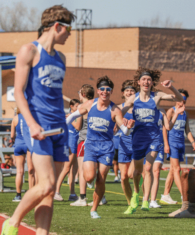  Harrison Township L’Anse Creuse senior Robert Galan and sophomores Alex Habarth and Aidan Daly, who are teammates in the 3,400 relay, run over to congratulate senior Cameron Sherrill as he finishes the last leg of the race. 