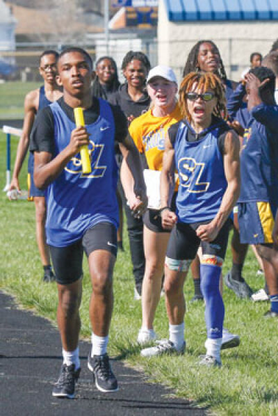  St. Clair Shores South Lake senior Anthony Gilmer, right, cheers on freshman teammate Nolan Love as he finishes the final leg of the 3,200 relay. 