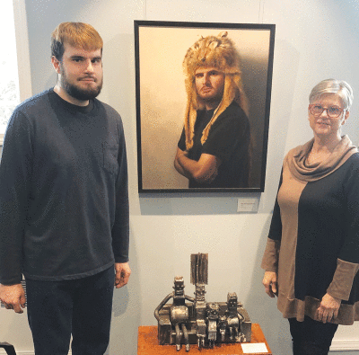  From left, Grosse Pointe Farms artists Max Rybinski and his mom, Jackie Rybinski, flank a portrait she painted of her son and her son’s metal sculpture of “The Simpsons.” These are among the works that are part of an exhibition by the Rybinskis called “Heat & Light.” 