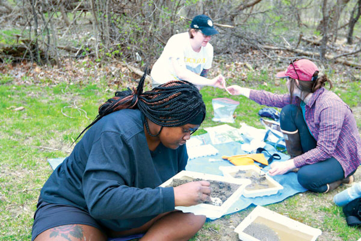  Kelly McCabe, of Ann Arbor, looks for bugs and tests water from the Rouge River in Southfield April 15. In the background are Anna Boegehold, of Dearborn, and her cousin, Serena Boegehold, of Clinton Township. 