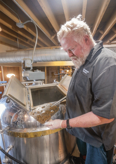  Brewmaster Todd Parker uses a tool to show off the hops while brewing at Rochester Mills Beer Co.  