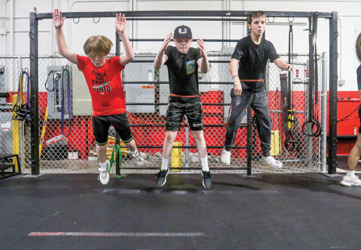  Nathan Roberts, left, Austin Holcomb, middle, and Clayton D’Hondt, right, work on banded broad jumps at Synergy Sports Performance Training. 