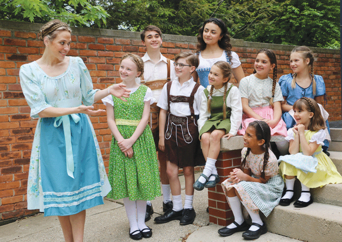  Annie Kordas, as Maria, left, takes the von Trapp children outside for an outing in Grosse Pointe Theatre’s production of “The Sound of Music.” The family is played by, in the back row, from left, Benjamin Ackley and Christina Jarad; middle row, from left, Reese Straske, Silas Beckett, Sloane Kordas, Jude Beckett and Cecile Kordas; and sitting on steps, from left, Anna Steiger and Charlotte Cullen.  