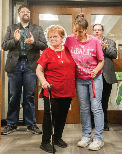  Linda Corbett, front left, widow of Robert Corbett, is  embraced by Madison Heights Mayor Roslyn Grafstein at a dedication ceremony May 8 for the new Robert J. Corbett  Youth Room. Behind them is Mayor Pro Tem Mark Bliss, left, and City Councilman Sean Fleming.  