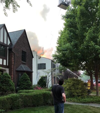  A neighbor watches as flames shoot from the roof of a home in the 400 block of Lincoln Road in Grosse Pointe City. 