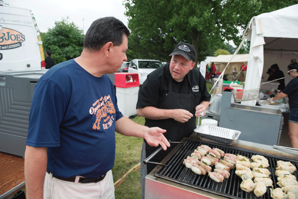   Jim Amato, of Clinton Township, left, and Vince & Joe’s Gourmet Markets cook Chuck Burns, of Roseville, talk about grilling spiedini during a previous Festa Italiana at Freedom Hill County Park in Sterling Heights. 