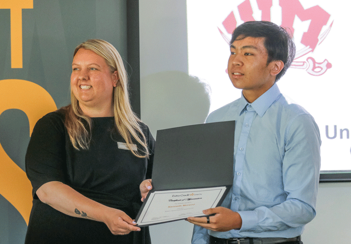  School and Community Relations Coordinator Lacey Cornell, left, presents Kenneth Moreno, of Warren Mott High School, with his award for receiving a $1,000 scholarship.  