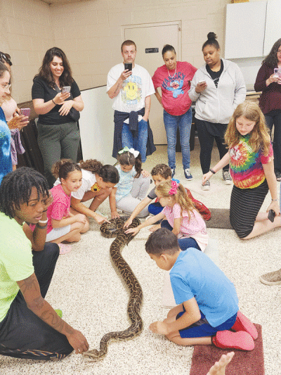  Children meet a snake at the Utica Public Library during the Reptarium’s presentation June 14. The visit was part of the library’s summer reading program.  