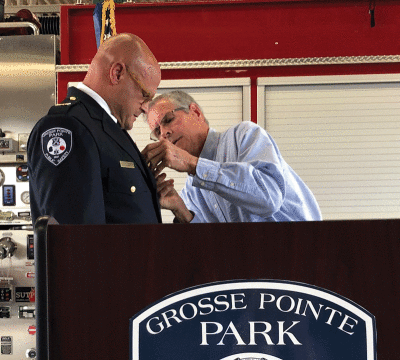  Grosse Pointe Park Public Safety Director James Bostock’s father, Bill Bostock, pins his son’s new badge on his uniform. 