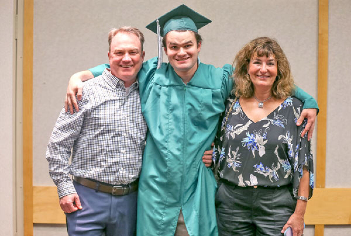 Matt Heslop poses for a photo with his parents, John and Linda Heslop, following his Novi Adult Transition Center graduation ceremony June 8. 