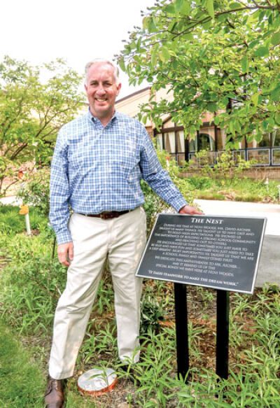  Novi Woods Principal David Ascher poses with a commemorative plaque dedicating the Nest area at Novi Woods Elementary School to his legacy at the school on May 22. Ascher was heavily involved in bringing the Nest outdoor learning area to fruition. 