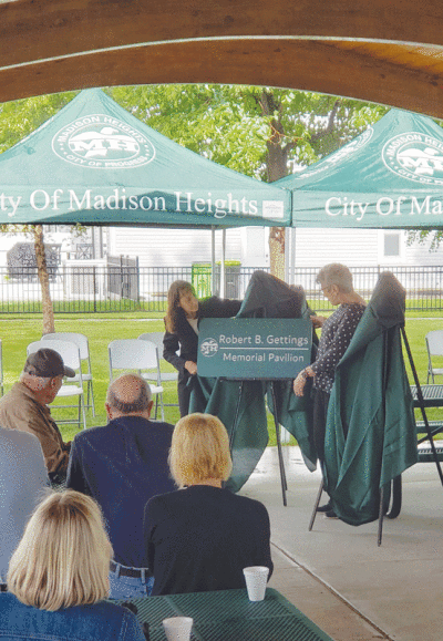  Madison Heights Mayor Roslyn Grafstein unveils a plaque dedicating the pavilion at Monroe Park in honor of the late Madison Heights City Councilman Robert Gettings June 26. Gettings’ cousin, Barbara Kastle, right, was also in attendance 