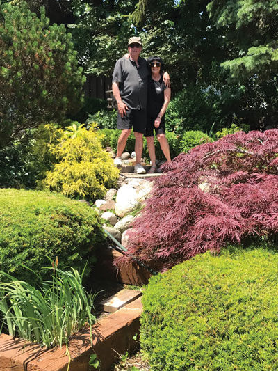  Harvey and Margaret McLand stand among their garden, one of six that will be featured in this year’s garden walk hosted by the Troy Garden Club. 