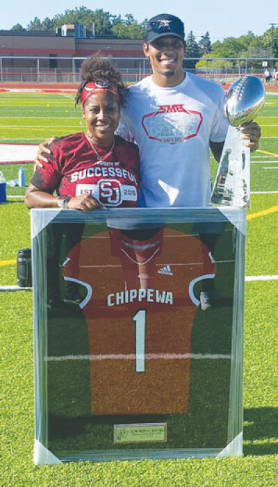  Sean Murphy-Bunting and his mother, Kim Murphy, stand together showcasing his framed Chippewa Valley jersey and the coveted Lombardi Trophy. 
