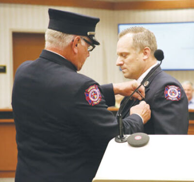  Lt. Ray Yonkowski, of the Macomb Township Fire Department, pins a badge on his son, Sgt. Kyle Yonkowski, of the Macomb Township Fire Department, during a badge presentation ceremony. 