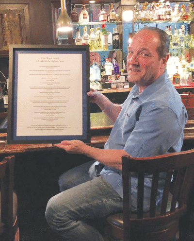 Former Grosse Pointe Park Public Safety Director Bryan Jarrell holds a framed poster with quotes, which the department’s newest hire felt applied to him, during a party in his honor June 8  at the Cabbage Patch Saloon. 
