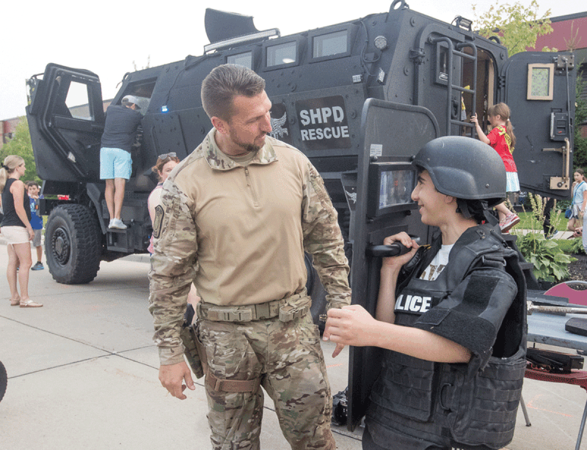  Sterling Heights police Officer Ken Mercer helps Emmanuel Gorgies, 11, from Sterling Heights, try on equipment used by the Special Response Team at the Sterling Heights Police Department’s National Night Out Aug. 1.  