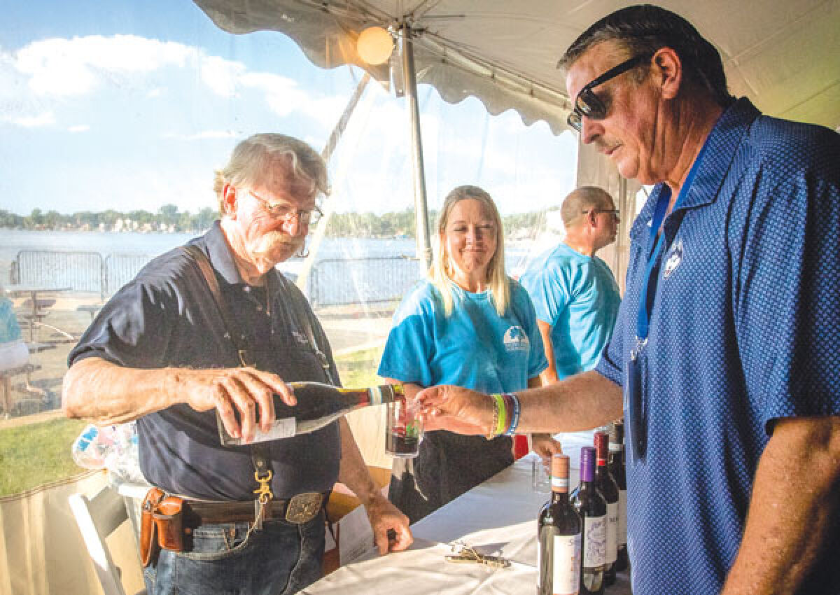  Lee Hershey, aka “the Wine Guy” from Novi Fine Wine & Liquor, pours a drink for Jay Dooley, chair of  the Novi Parks, Recreation and Cultural Services Commission, during the Novi Parks Foundation’s Pour on the Shore fundraiser at Pavilion Shore Park July 28.  