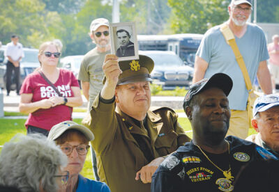  Air Force veteran Patrick Kopytek holds up a picture of his dad, Walter, who served in the Navy during World War II. Kopytek is wearing a World War ll uniform. 
