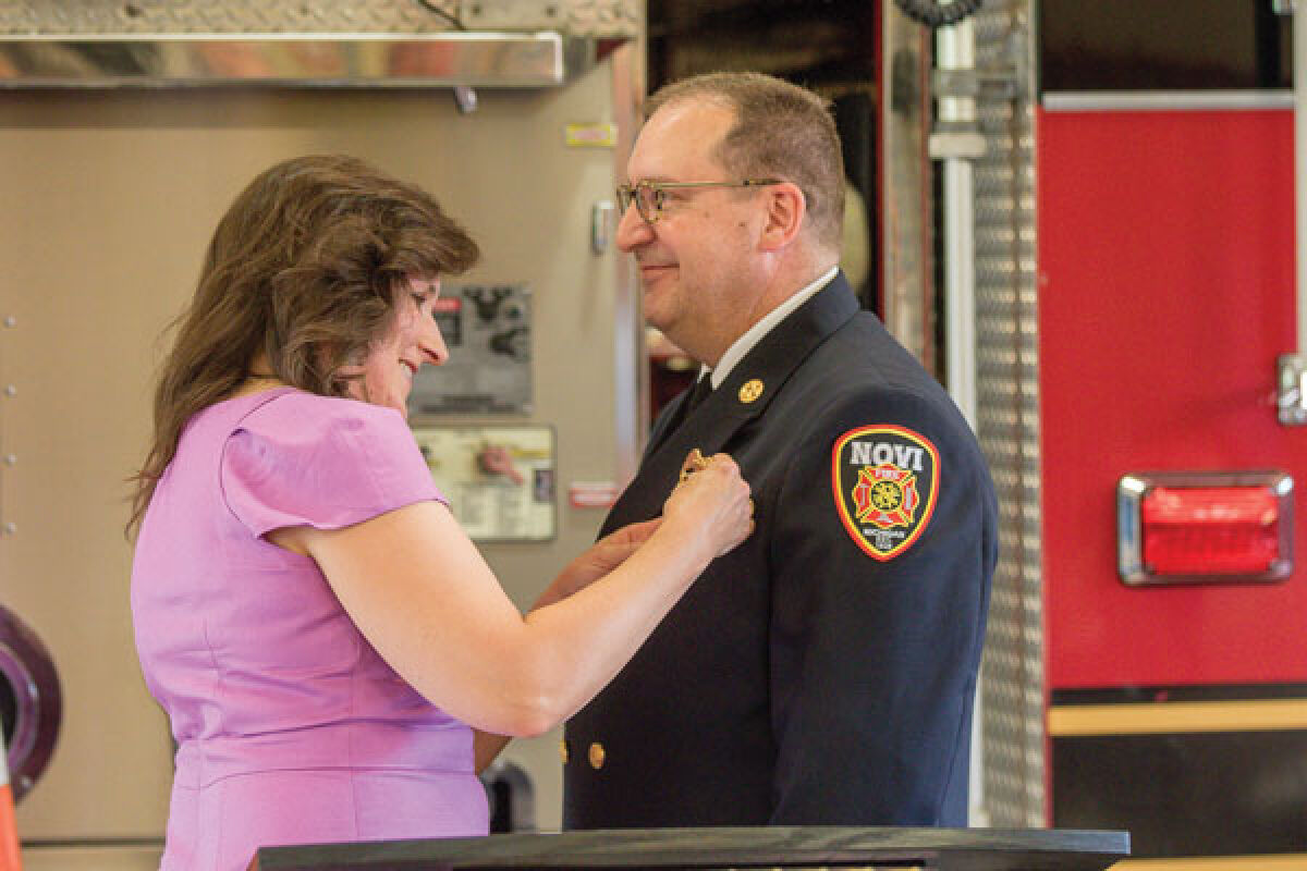 Renee Martin pins the Novi fire chief’s badge on husband John’s uniform Aug. 8. 
