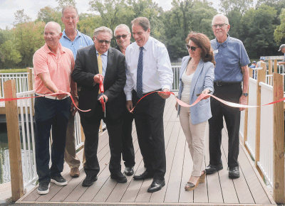  Shelby Township officials including Clerk Stanley T. Grot, with scissors, and Supervisor Rick Stathakis, center, cut a ribbon Aug. 24  to dedicate the completion of the first phase  of improvements to Heritage Lake on  the township’s municipal campus. 