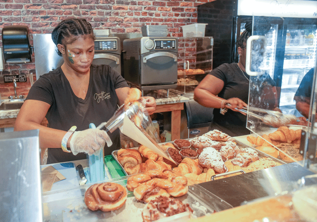  JayKayla Moses, a student at the Rising Stars Academy, bags baked goods during the Gather + Grounds grand opening Sept. 23.  