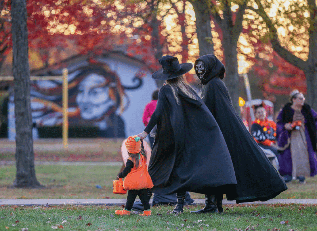  Costumed families walk the path at Civic Center Park in Madison Heights during last year’s Pumpkin Walk. This year’s event has been rebranded Trail of Treats.   