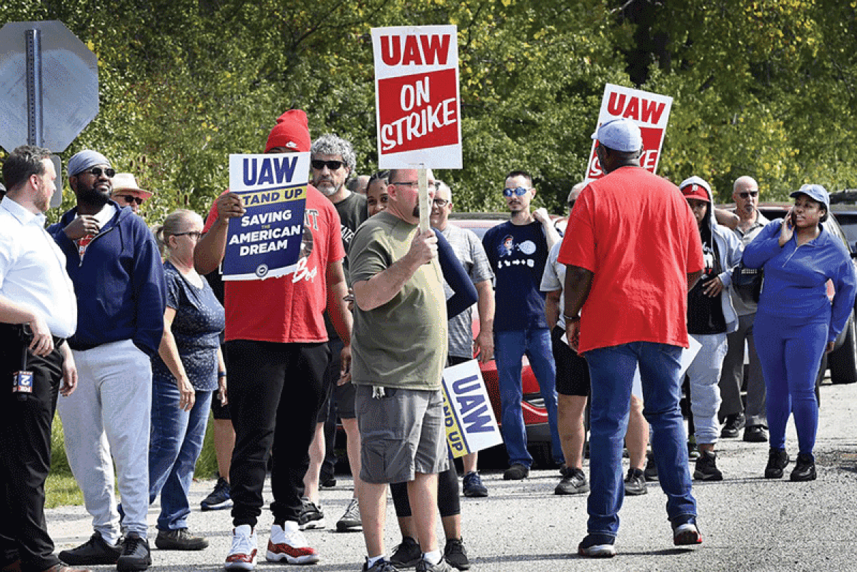  Workers at the two parts distribution centers operated by General Motors on two sides of Willow Run Airport grab signs to start their picketing Sept. 29.  