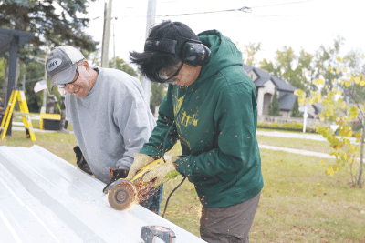  Arambulo cuts material for the pergola’s roof with help from Eagle Scout adviser Doug Gettleson.  