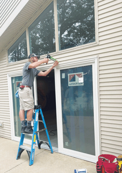   Cameron Hunsberger, from Renewal by Andersen, caulks a door at the Howell Nature Center. 
