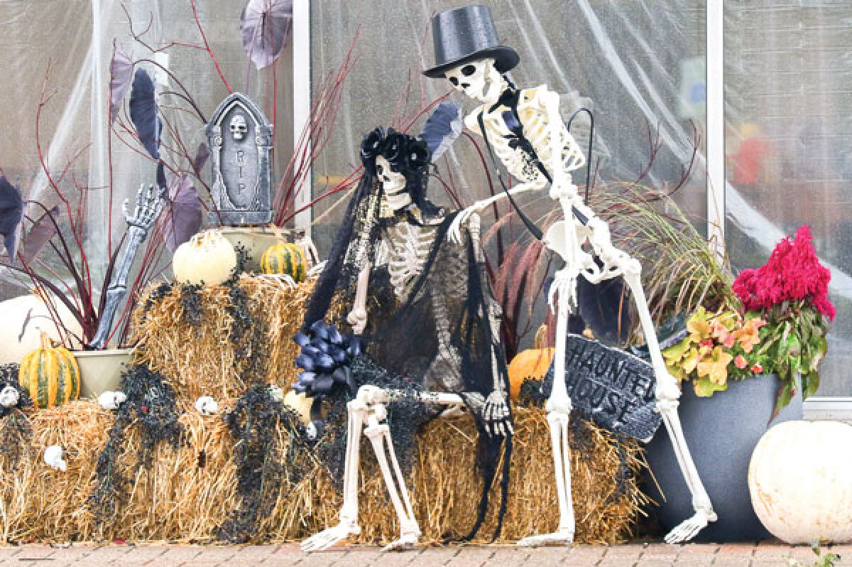 Two skeletons, dressed up for Skelebration, sit on hay bales outside of The Rustic Root. 