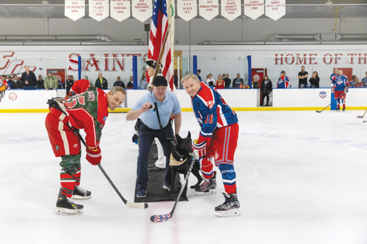  Players get ready for a puck drop at the Power Play for Heroes in 2022, as service dog recipient Matt McMurray and his dog, Cobalt, stand ready for the faceoff. 