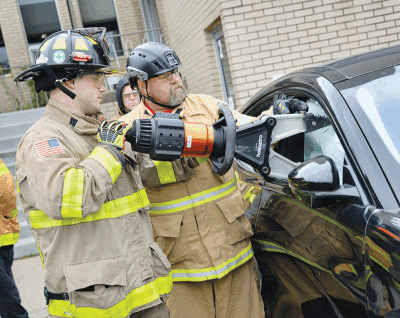  Firefighter Sebastian Masseth uses the spreader on a vehicle while Steve Kimker, of Rescue Redefined, gives instructions during the exercise. 