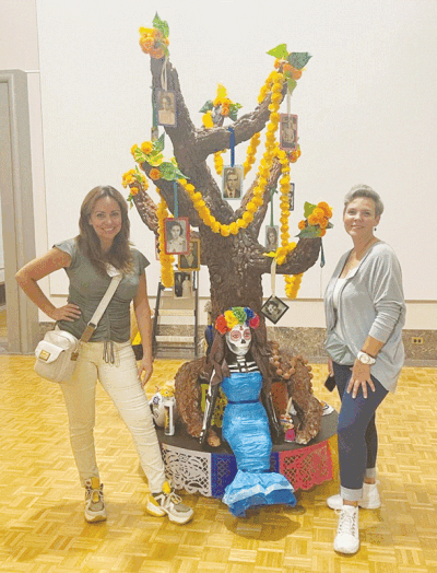  Valeria Zozaya and Maritere De La Fuente, both of Rochester Hills, pose next to their ofrenda, which is currently on display at the Detroit Institute of Arts.  