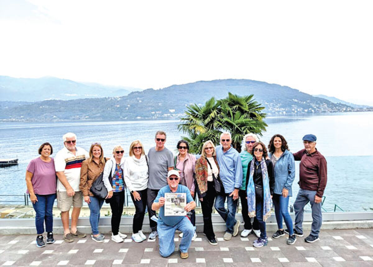  Members from Lakeview classes 1969 through 1972 stand in front of Lake Maggiore in Italy. From left: Veda (Brooklier) Hall, Dennis Maguet, Marilyn (Huber) Maguet, Theresa (Mossiaux) Serra, Sue (Rae) Springer, Fred Springer, Sheryl (Sulenski) Furnas, Cathy (Cooney) Trombley, Chuck Trombley, Paul Huber, Judy (Kelley) Huber, Yvonne (Maison) Corcoran and Glenn Corcoran. At center is Chuck Hall, holding a copy of the St. Clair Shores Sentinel.  