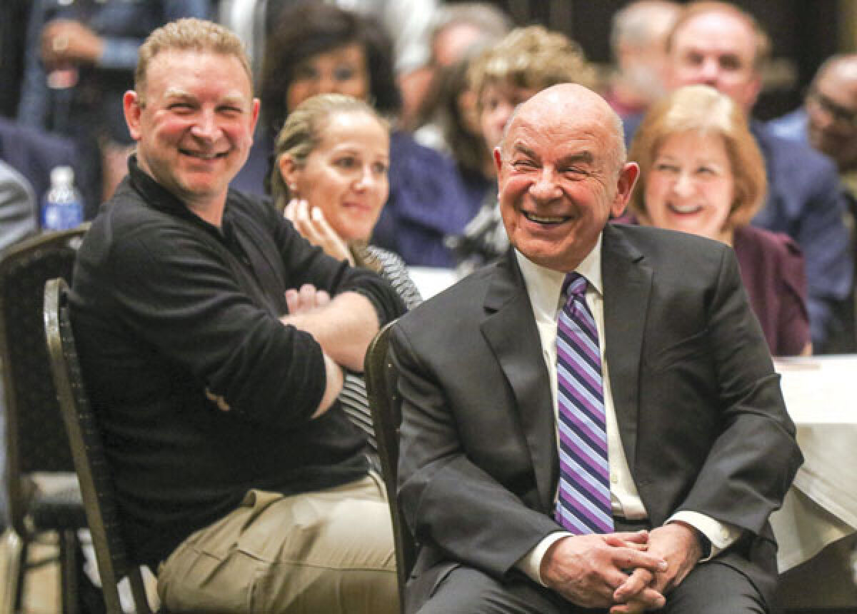  Novi Mayor Bob Gatt and his son, Robert, smile as they listen to former Novi Director of Public Safety/Police Chief David Molloy speak about Gatt during a farewell celebration held by the city Oct. 27 at Suburban Collection Showplace.  