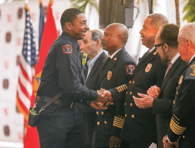  Warren Fire Commissioner Skip McAdams, center, shakes the hand of cadet probationary firefighter/paramedic Christopher Quinn. 