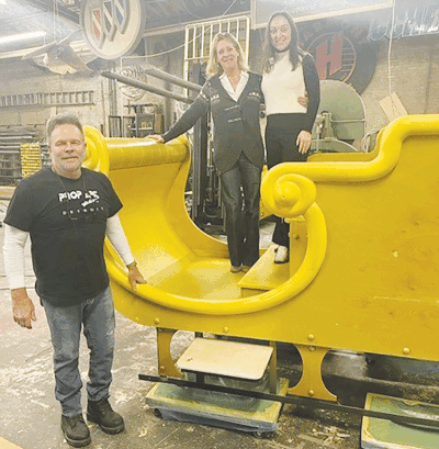   From left, Prop Art Studio owner Michael Stapleton, Grosse Pointe Chamber of Commerce President Jennifer Boettcher and GPCC Membership & Event Coordinator Abigail Turnbull check out Santa’s new sleigh as it’s being built.  