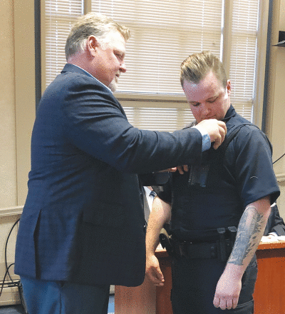  Dad Cliff Howe pins the badge on son Billy Clifton Howe’s uniform after the younger Howe is sworn in as a Grosse Pointe Shores Public Safety officer May 17 at Shores City Hall. 