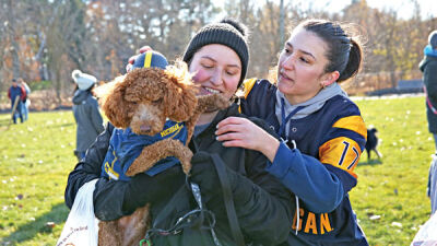  Rose, center, and Isabella Licavoli try putting a helmet on dog Gus, the winner of the best dressed contest at the opening of Macomb Township’s Pitchford Park dog park. 