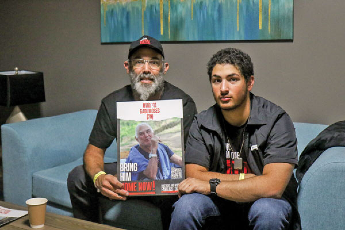  Yair Moses, 49, left, holds a photo of his father, Gadi Moses, 79, who was taken captive with other hostages Oct. 7 from their kibbutz in Israel. Yair and his son, Erez Moses, 16, right, were in Detroit during the week of Dec. 4 to bring awareness to Hostages and Missing Families Forum, a group of volunteers dedicated to bringing the hostages home now. 
